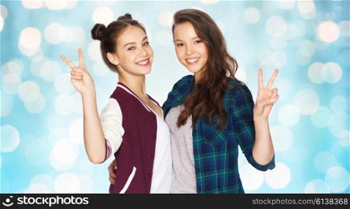 people, friends, teens and friendship concept - happy smiling pretty teenage girls hugging and showing peace hand sign over blue holidays lights background