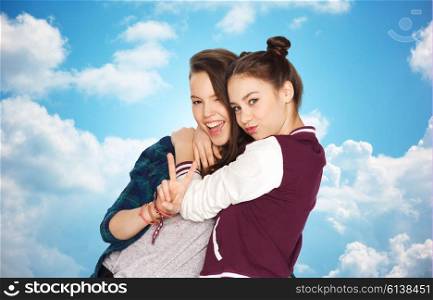 people, friends, teens and friendship concept - happy smiling pretty teenage girls hugging and showing peace hand sign over blue sky and clouds background