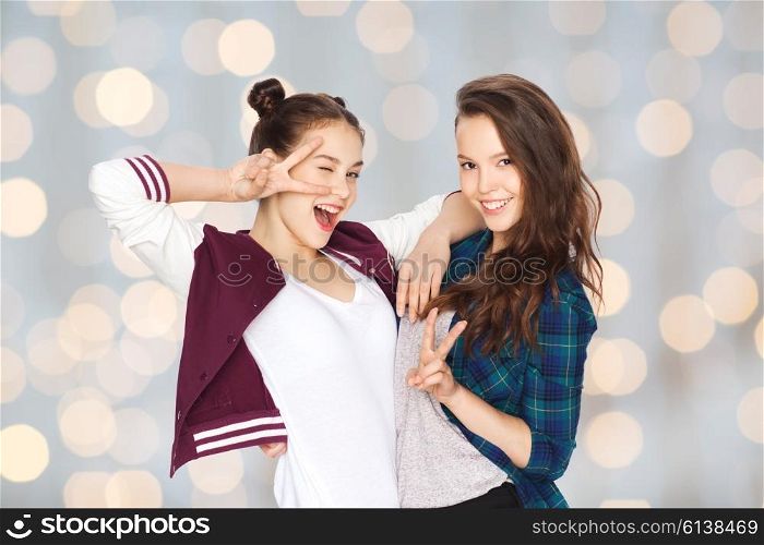 people, friends, teens and friendship concept - happy smiling pretty teenage girls showing peace hand sign over holidays lights background