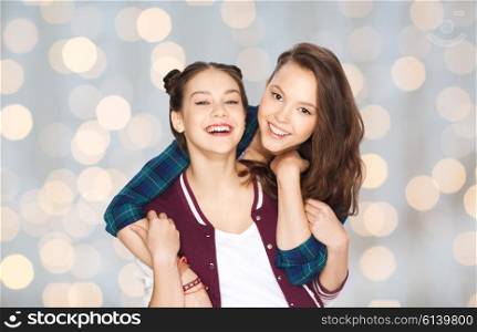 people, friends, teens and friendship concept - happy smiling pretty teenage girls hugging over holidays lights background