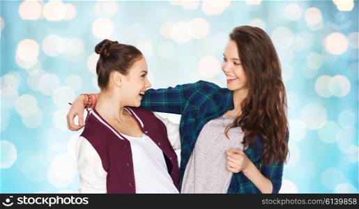 people, friends, teens and friendship concept - happy smiling pretty teenage girls hugging over blue holidays lights background
