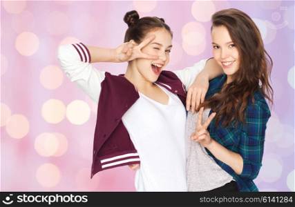 people, friends, teens and friendship concept - happy smiling pretty teenage girls showing peace hand sign over pink holidays lights background