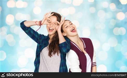 people, friends, teens and friendship concept - happy smiling pretty teenage girls having fun and making faces over blue holidays lights background