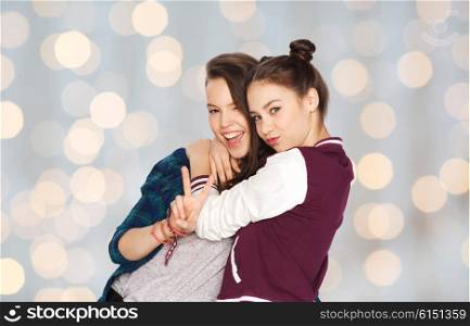 people, friends, teens and friendship concept - happy smiling pretty teenage girls hugging and showing peace hand sign over holidays lights background