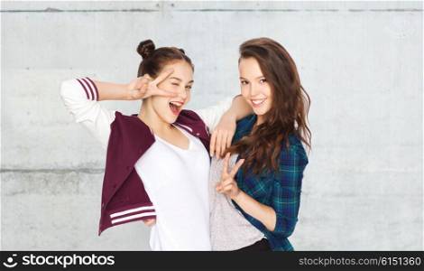 people, friends, teens and friendship concept - happy smiling pretty teenage girls showing peace hand sign over gray stone wall background