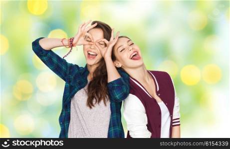 people, friends, teens and friendship concept - happy smiling pretty teenage girls having fun and making faces over green summer holidays lights background