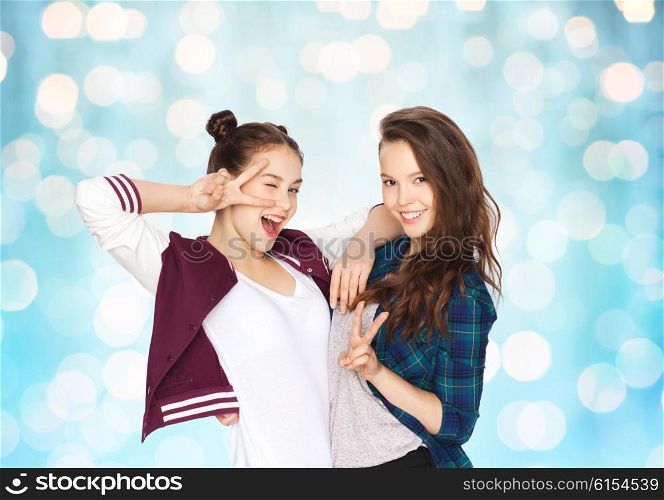 people, friends, teens and friendship concept - happy smiling pretty teenage girls showing peace hand sign over blue holidays lights background
