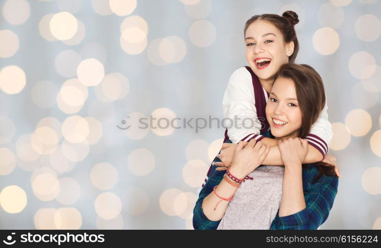 people, friends, teens and friendship concept - happy smiling pretty teenage girls hugging over holidays lights background