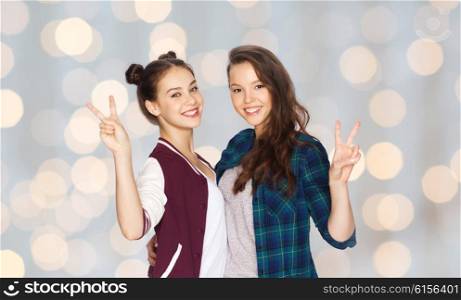 people, friends, teens and friendship concept - happy smiling pretty teenage girls hugging and showing peace hand sign over holidays lights background