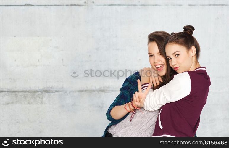 people, friends, teens and friendship concept - happy smiling pretty teenage girls hugging and showing peace hand sign over gray stone wall background