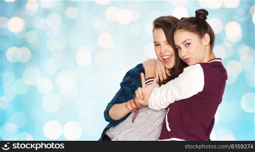 people, friends, teens and friendship concept - happy smiling pretty teenage girls hugging and showing peace hand sign over blue holidays lights background
