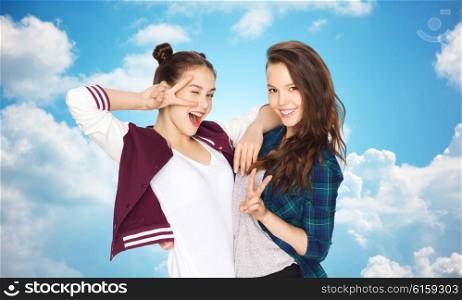 people, friends, teens and friendship concept - happy smiling pretty teenage girls showing peace hand sign over blue sky and clouds background
