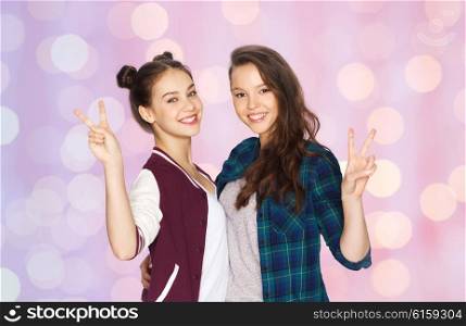 people, friends, teens and friendship concept - happy smiling pretty teenage girls hugging and showing peace hand sign over pink holidays lights background