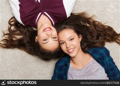 people, friends, teens and friendship concept - happy smiling pretty teenage girls lying on floor