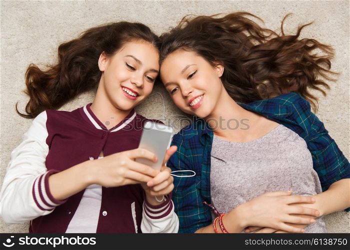 people, friends, teens and technology concept - happy smiling pretty teenage with smartphones and earphones listening to music