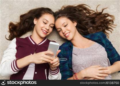 people, friends, teens and technology concept - happy smiling pretty teenage with smartphones and earphones listening to music