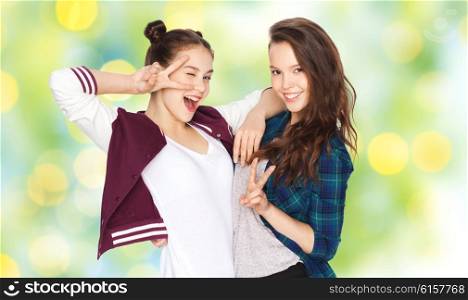 people, friends, teens, summer and friendship concept - happy smiling pretty teenage girls showing peace hand sign over green holidays lights background