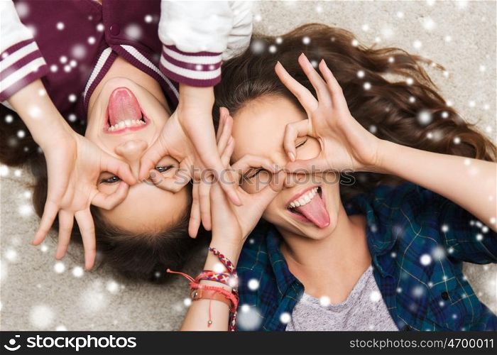 people, friends, winter, christmas and friendship concept - happy smiling pretty teenage girls having fun and making faces over snow