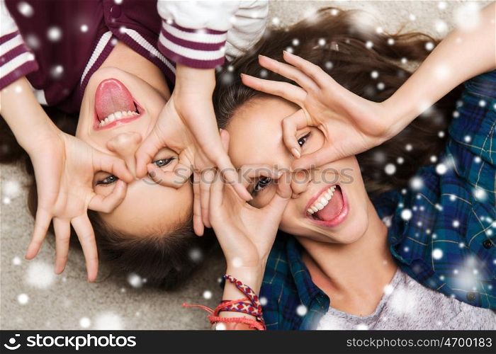 people, friends, winter, christmas and friendship concept - happy smiling pretty teenage girls having fun and making faces over snow