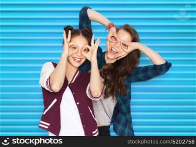people, friendship and fun concept - happy smiling pretty teenage girls or friends making faces over blue ribbed background. happy smiling pretty teenage girls having fun
