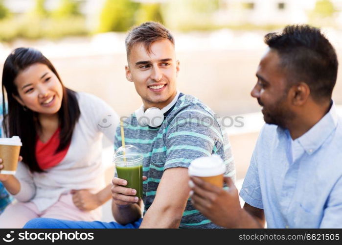 people, friendship and international concept - group of happy friends drinking coffee and juice talking in city. friends drinking coffee and juice talking in city