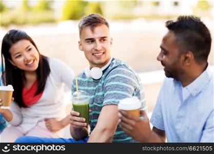 people, friendship and international concept - group of happy friends drinking coffee and juice talking in city. friends drinking coffee and juice talking in city