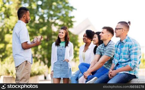 people, friendship and international concept - group of happy friends talking in park. happy international friends talking in park