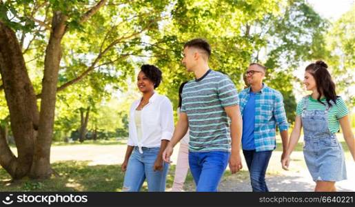 people, friendship and international concept - group of happy friends walking in park. happy international friends walking in park