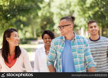 people, friendship and international concept - group of happy friends walking outdoors. group of happy international friends outdoors. group of happy international friends outdoors