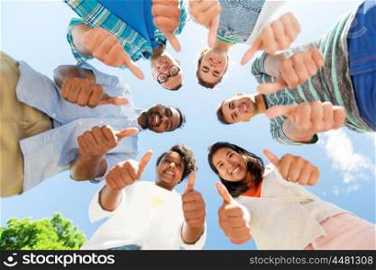 people, friendship and international concept - group of happy smiling friends outdoors standing in circle and showing thumbs up. happy friends showing thumbs up standing in circle. happy friends showing thumbs up standing in circle