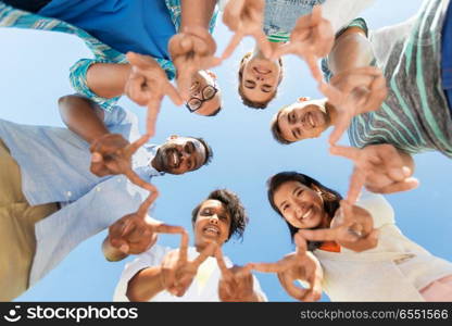 people, friendship and international concept - group of happy smiling friends outdoors standing in circle and showing peace hand sign. happy friends showing peace standing in circle. happy friends showing peace standing in circle