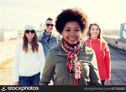 people, friendship and international concept - happy african american young woman or teenage girl in front of her friends on city street