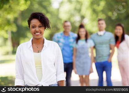 people, friendship and international concept - happy smiling african american woman and group of friends outdoors. group of happy international friends outdoors. group of happy international friends outdoors