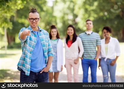 people, friendship and international concept - happy smiling man in glasses and group of happy friends outdoors. group of happy international friends outdoors. group of happy international friends outdoors