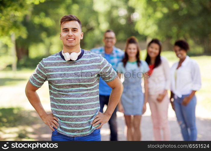 people, friendship and international concept - happy smiling young man and group of happy friends outdoors. group of happy international friends outdoors. group of happy international friends outdoors