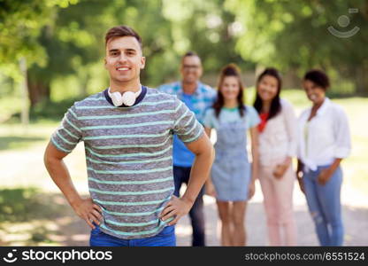 people, friendship and international concept - happy smiling young man and group of happy friends outdoors. group of happy international friends outdoors. group of happy international friends outdoors