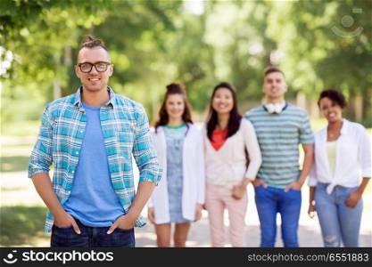 people, friendship and international concept - happy smiling young man and group of happy friends outdoors. group of happy international friends outdoors. group of happy international friends outdoors