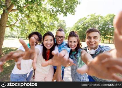 people, friendship and international concept - happy smiling young woman and group of happy friends taking selfie outdoors. group of happy international friends taking selfie. group of happy international friends taking selfie