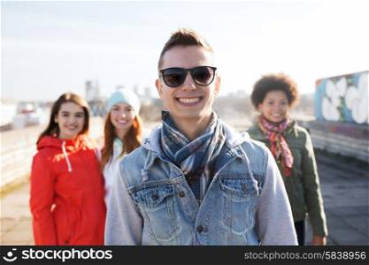 people, friendship and international concept - happy young man or teenage boy in front of his friends on city street
