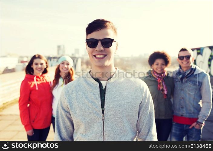 people, friendship and international concept - happy young man or teenage boy in front of his friends on city street