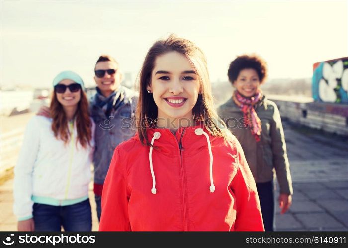 people, friendship and international concept - happy young woman or teenage girl in front of her friends on city street