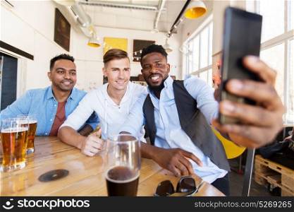 people, friendship and leisure concept - happy male friends drinking beer and taking selfie by smartphone at bar or pub. friends taking selfie and drinking beer at bar