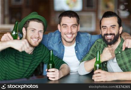 people, friendship and st patricks day concept - happy male friends drinking bottled beer and hugging at bar or pub. happy male friends drinking beer at bar or pub