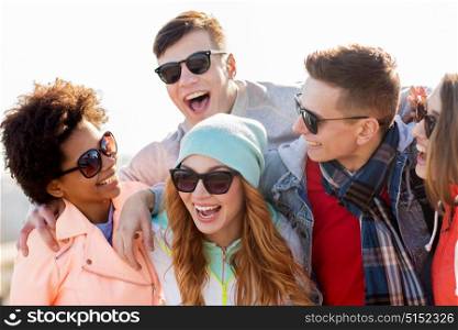 people, friendship and teenage concept - group of happy friends in sunglasses having fun and laughing outdoors. happy teenage friends in shades laughing outdoors