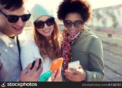 people, friendship, cloud computing and technology concept - group of smiling teenage friends with smartphone outdoors