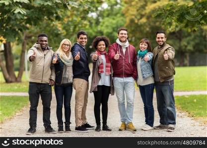 people, friendship, communication and international concept - group of happy friends showing thumbs up at autumn park