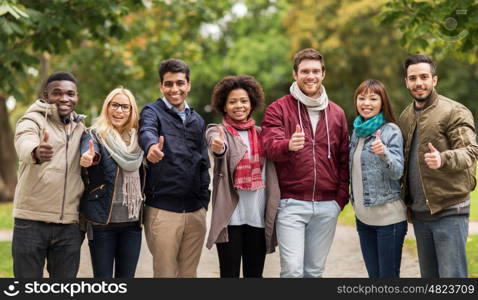 people, friendship, communication and international concept - group of happy friends showing thumbs up at autumn park