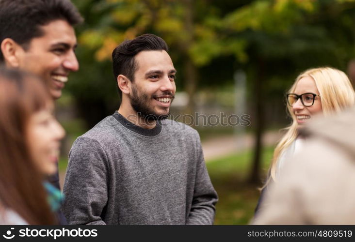 people, friendship, communication and international concept - group of happy friends walking along autumn park