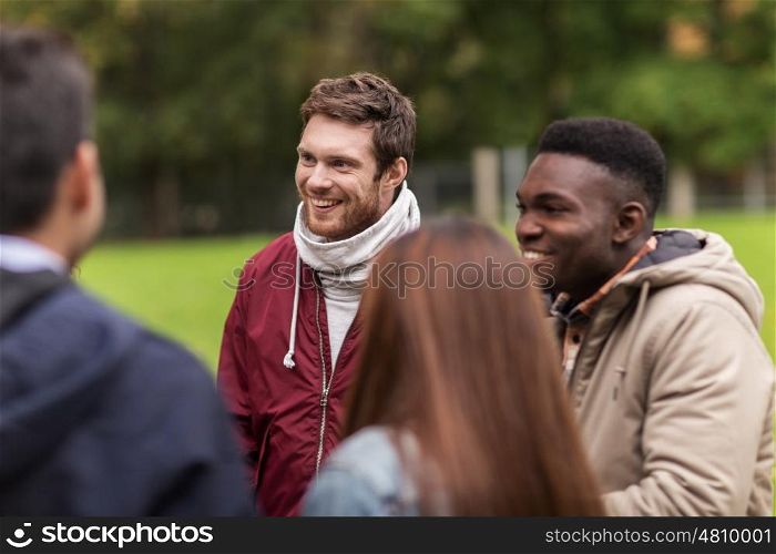 people, friendship, communication and international concept - group of happy friends walking along autumn park