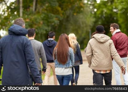 people, friendship, communication and international concept - group of happy friends walking along autumn park. happy friends walking along autumn park
